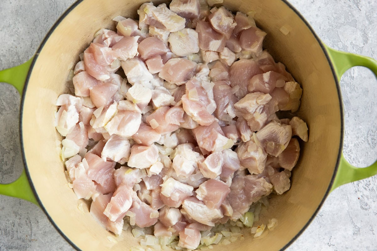 large pot full of chopped chicken and onions cooking.