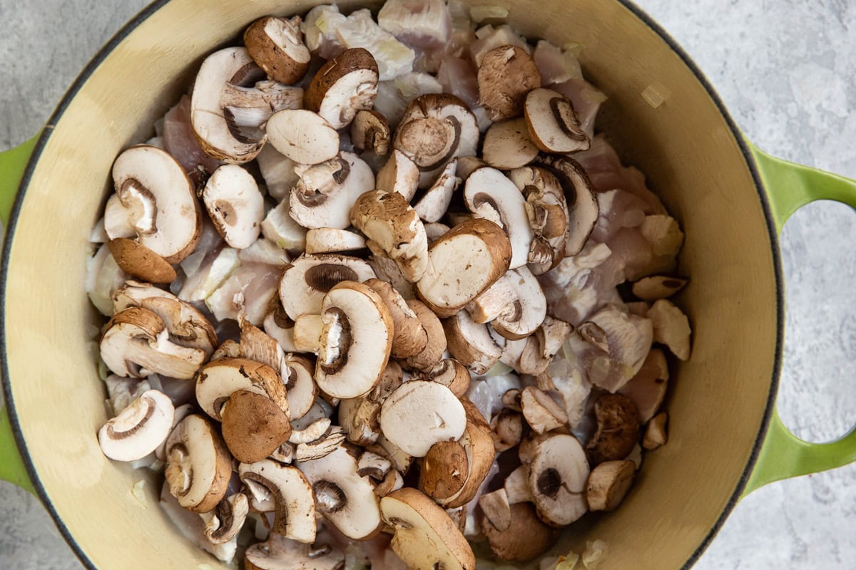 Large pot of chicken, mushrooms, and onions cooking.