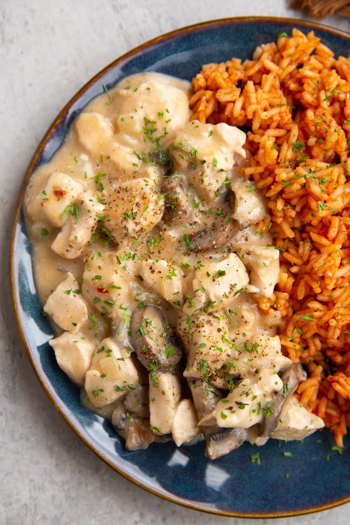 Chicken and creamy mushroom sauce with Mexican rice on a blue plate, ready to serve.