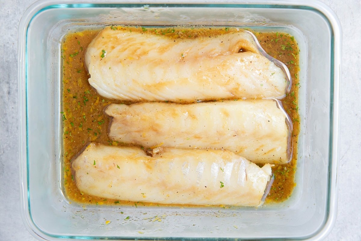 Fish marinating in a glass container full of marinade to make fish tacos.