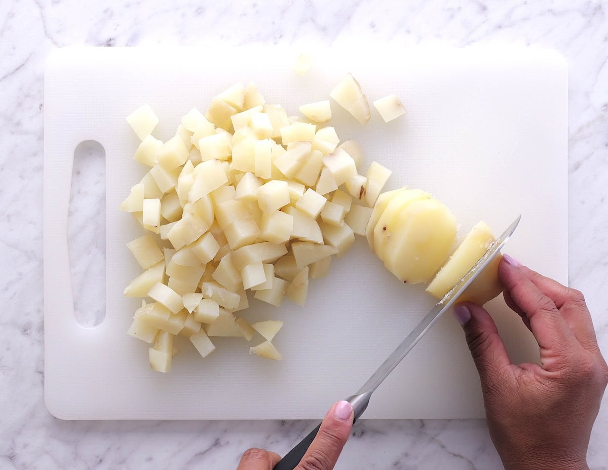 Hand chopping cooked potatoes into cubes.