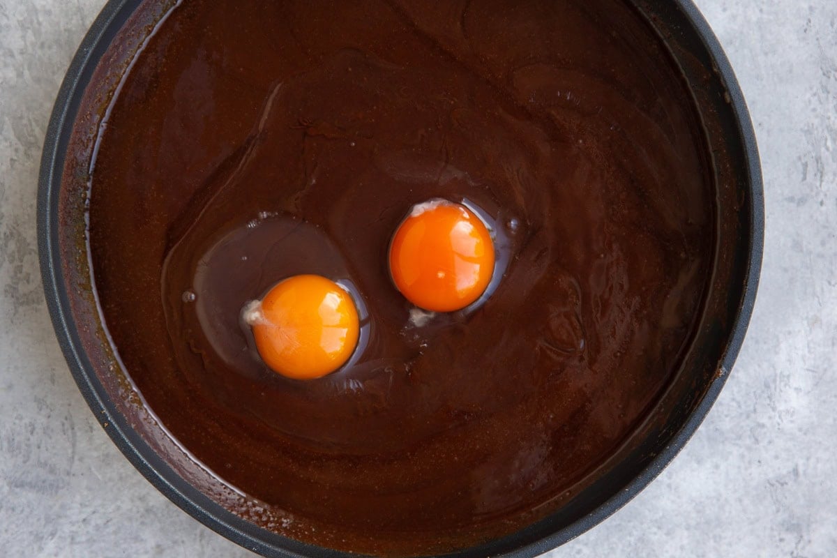 Skillet with melted chocolate and eggs to be mixed in.