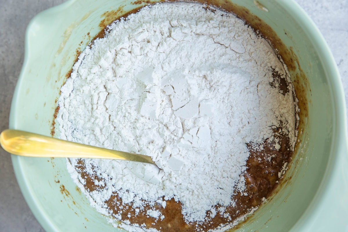 Dry ingredients on top of wet ingredients in a mixing bowl to make banana bread.