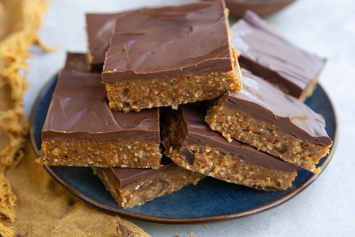 Stack of chocolate covered protein bars on a blue plate with a golden napkin.