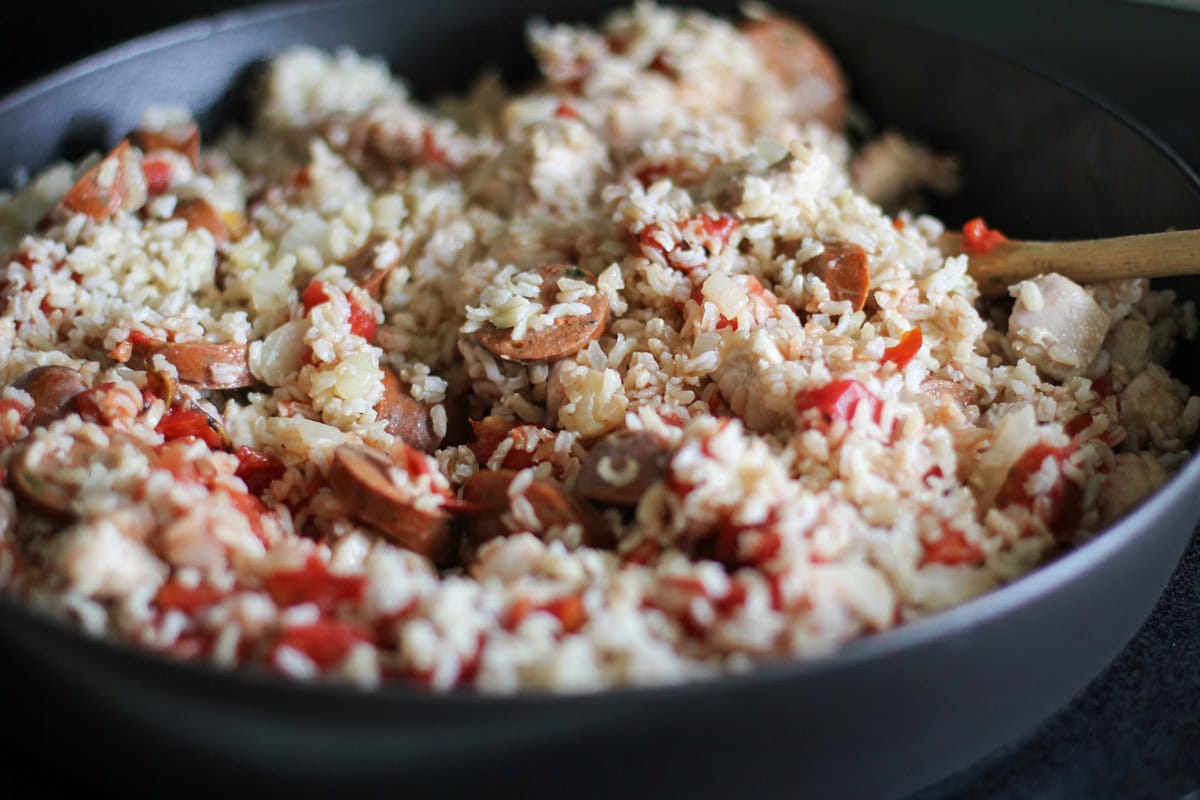 Rice, diced tomatoes, and sausage mixed into the skillet with chicken and onion.