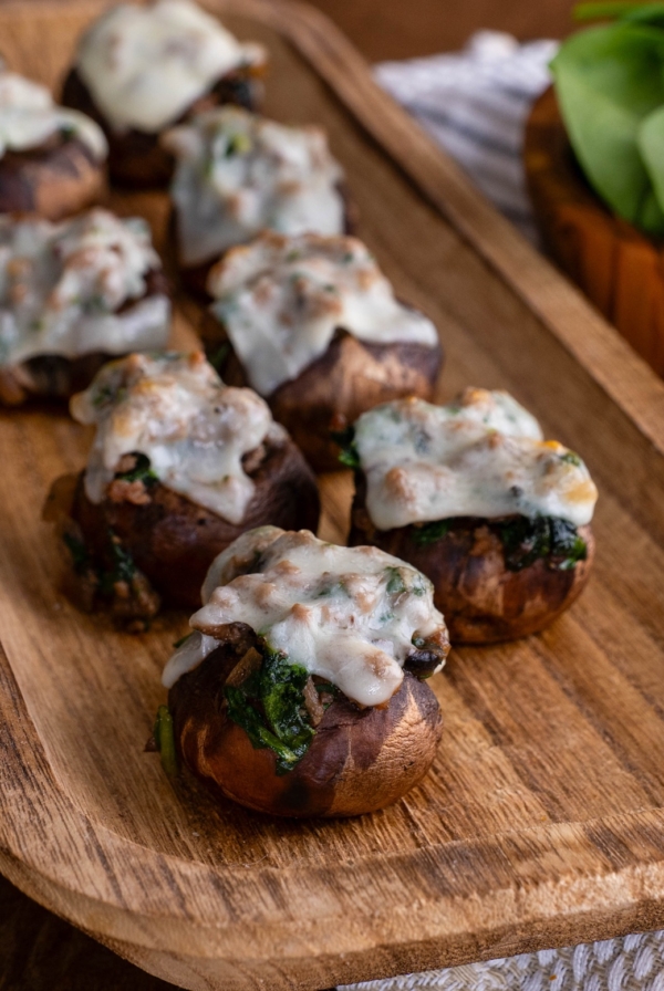 Stuffed mushrooms on a wooden platter, ready to serve.