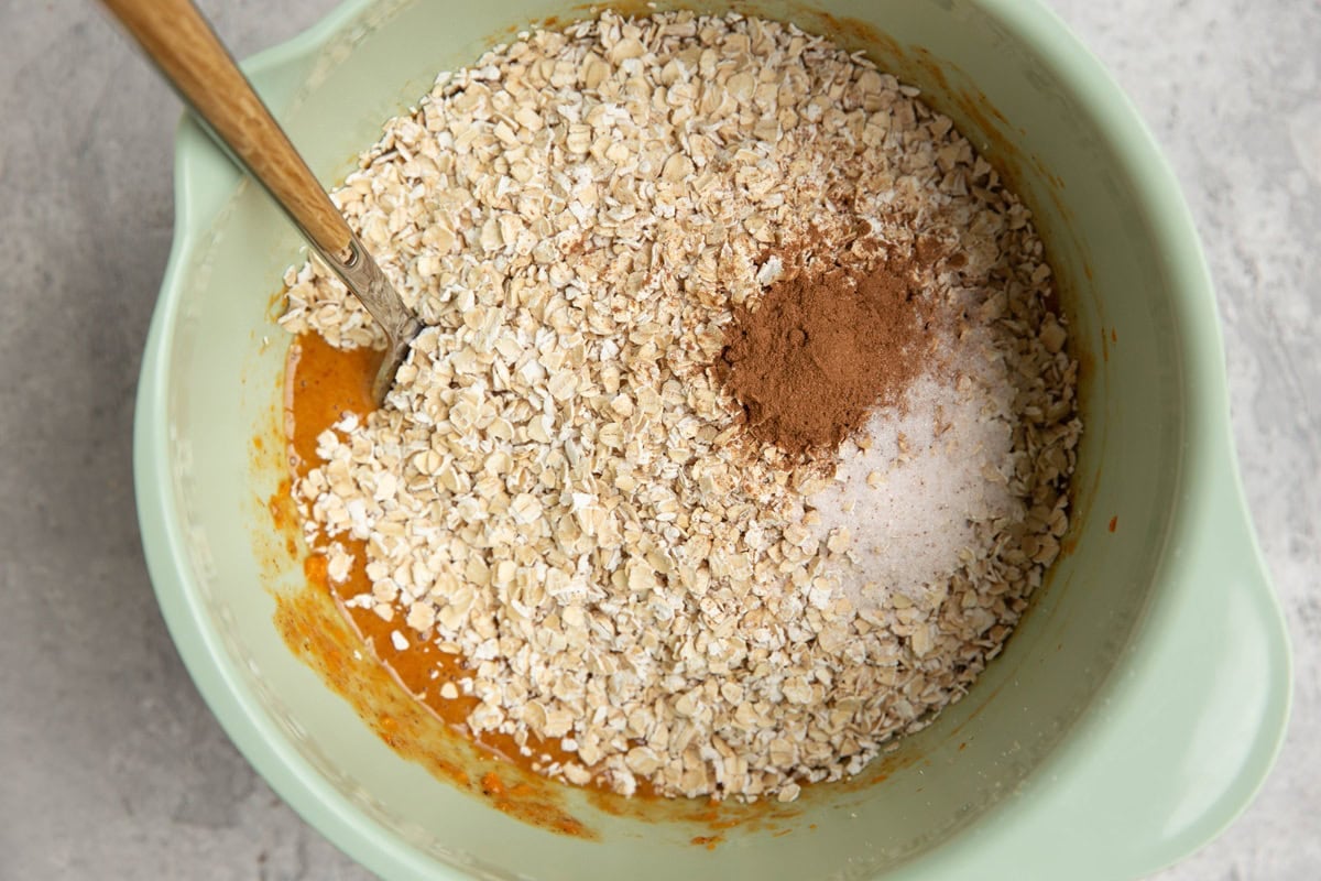 Mixing bowl with wet ingredients in the bottom and dry ingredients on top to make sweet potato cookies.
