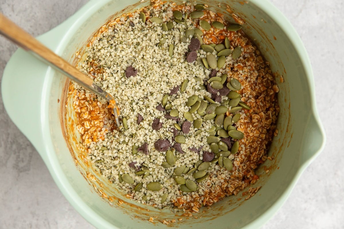 Chopped nuts, seeds, chocolate chips in a mixing bowl with sweet potato cookie dough to be mixed in.