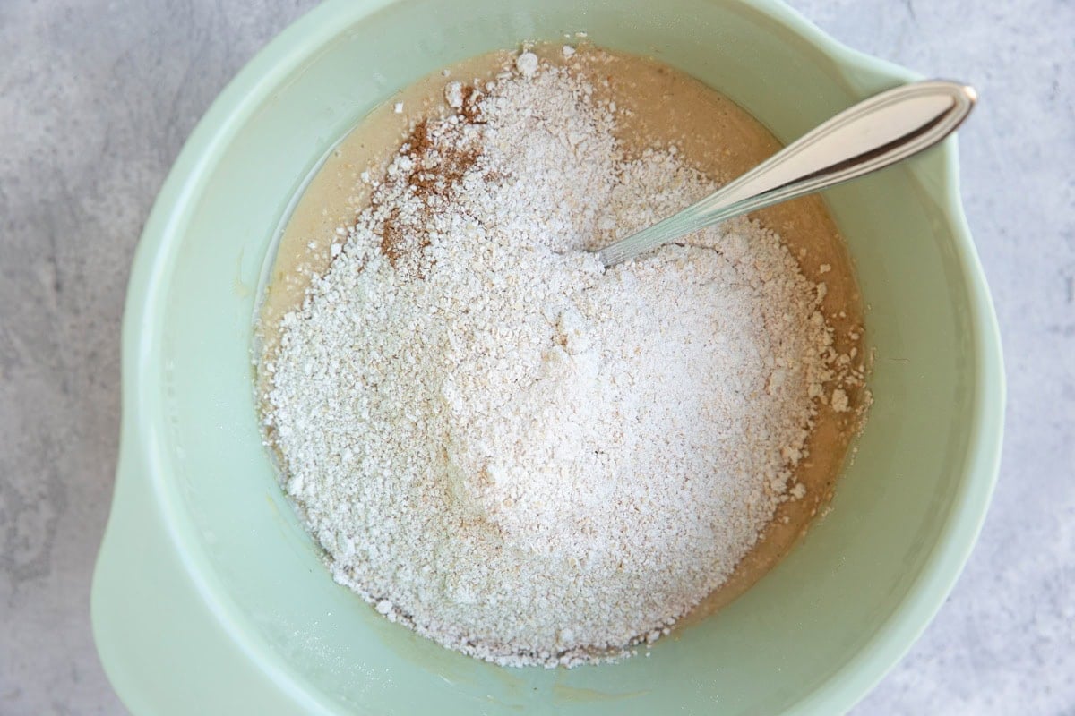 Mixing bowl full of wet ingredients with dry ingredients on top.