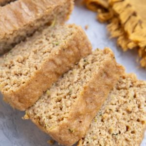 Loaf of yogurt zucchini bread cut into slices with a golden napkin in the background.