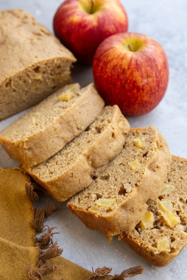 Almond Flour Apple Bread cut into slices on a backdrop with two fresh apples in the background.