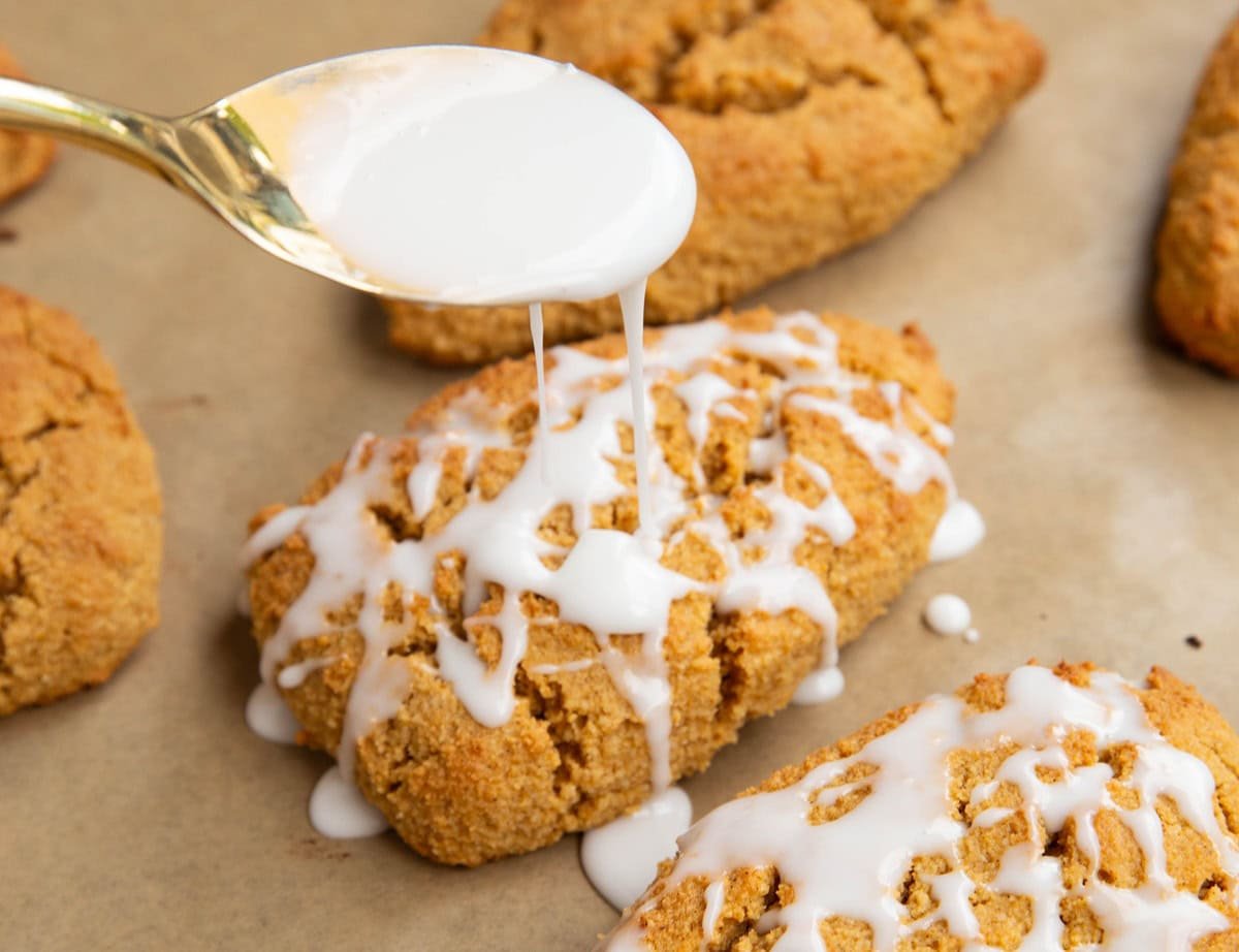 Pumpkin scones being drizzled with glaze.