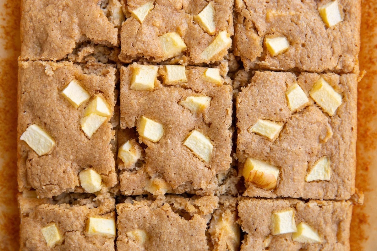 Applesauce cake cut into squares on a sheet of parchment paper.