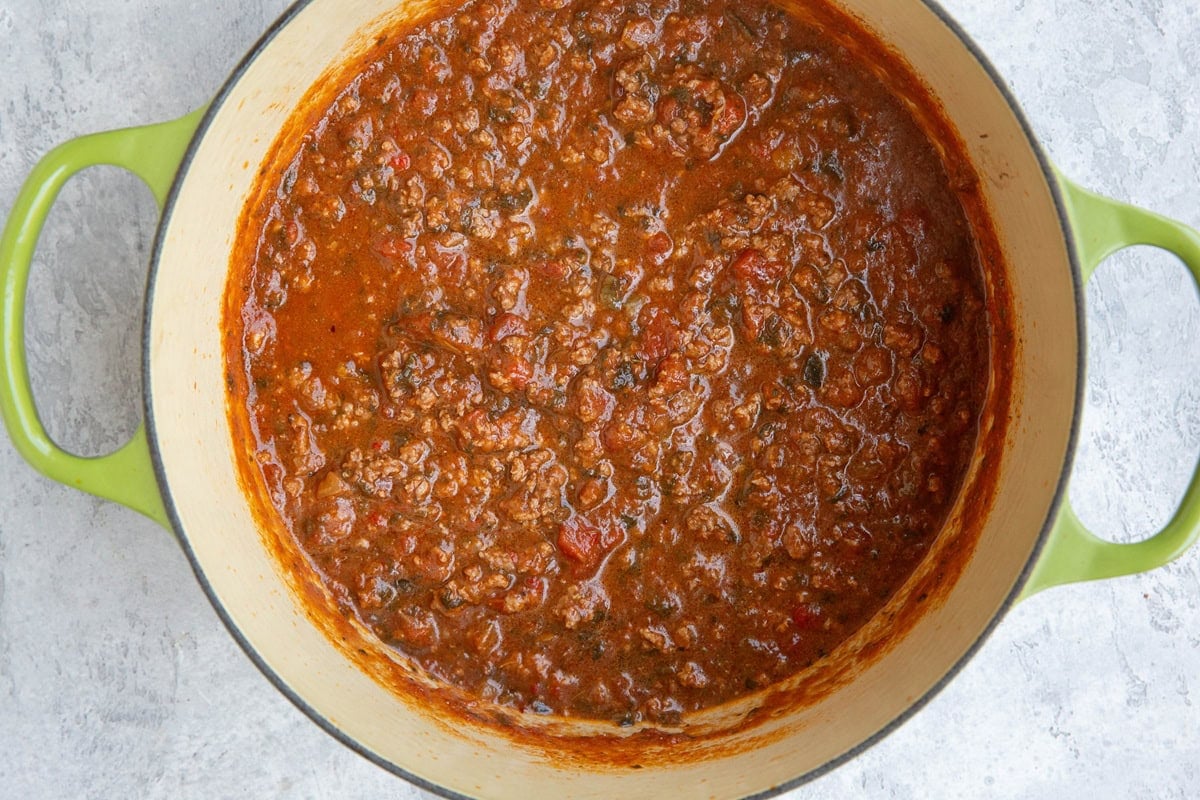Dutch oven full of red sauce with red meat