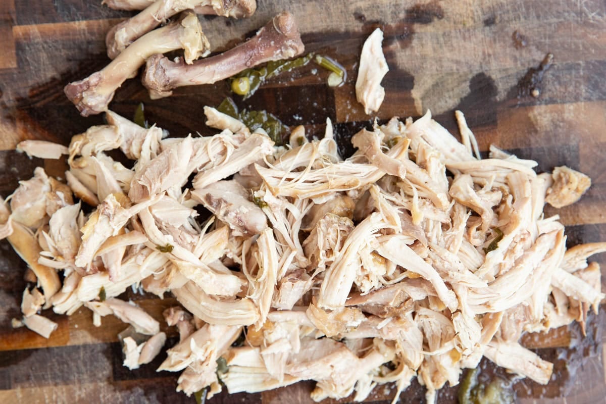 Chicken thighs shredded on a cutting board to go into chicken stew.