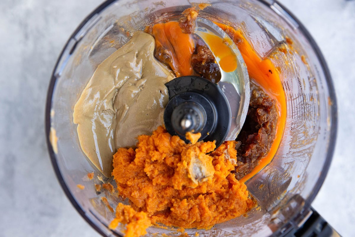Food processor full of dates, pumpkin puree, sunflower seeds, and eggs.