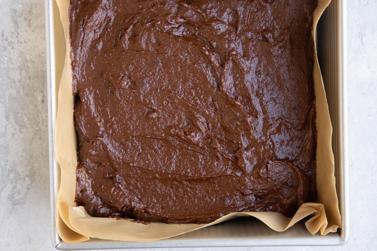 8 inch baking pan with date brownie batter inside, ready to bake.