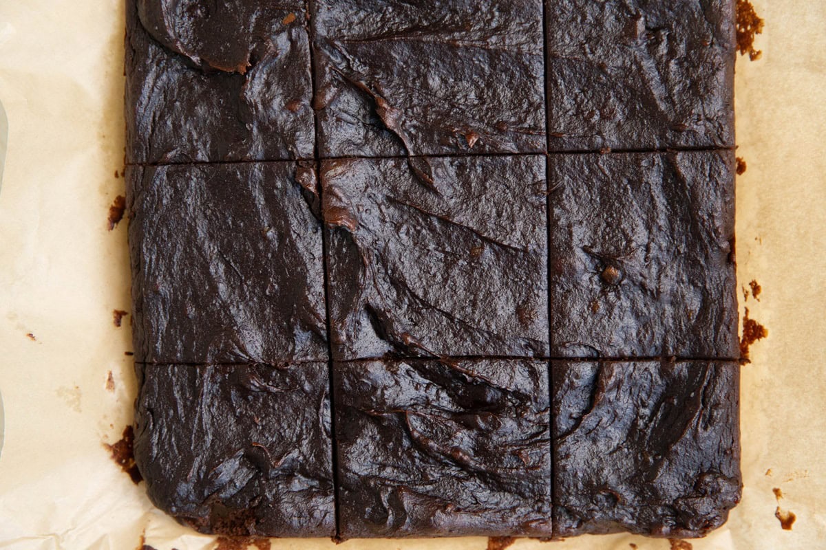 Brownies cur into squares on a sheet of parchment paper.