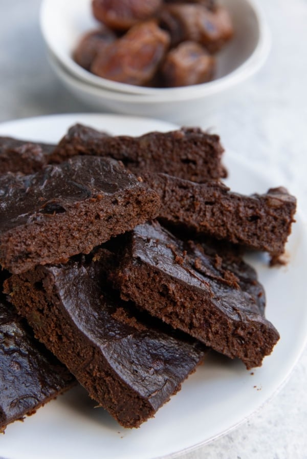 Plate of date brownies with a bowl of dates in the background.