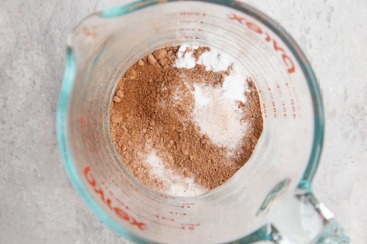 Measuring cup of cocoa powder, baking soda, sea salt, and pumpkin spice