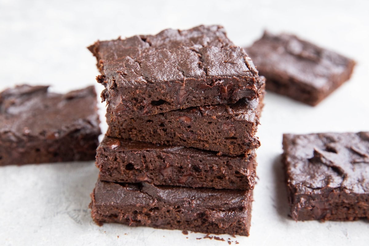 Four pumpkin brownies stacked on top of each other with three additional brownies surrounding the stack.