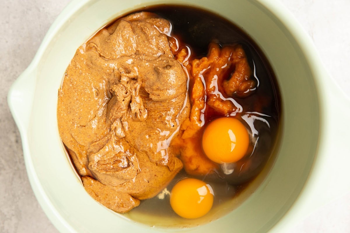 Pumpkin puree, almond butter, and eggs in a mixing bowl.