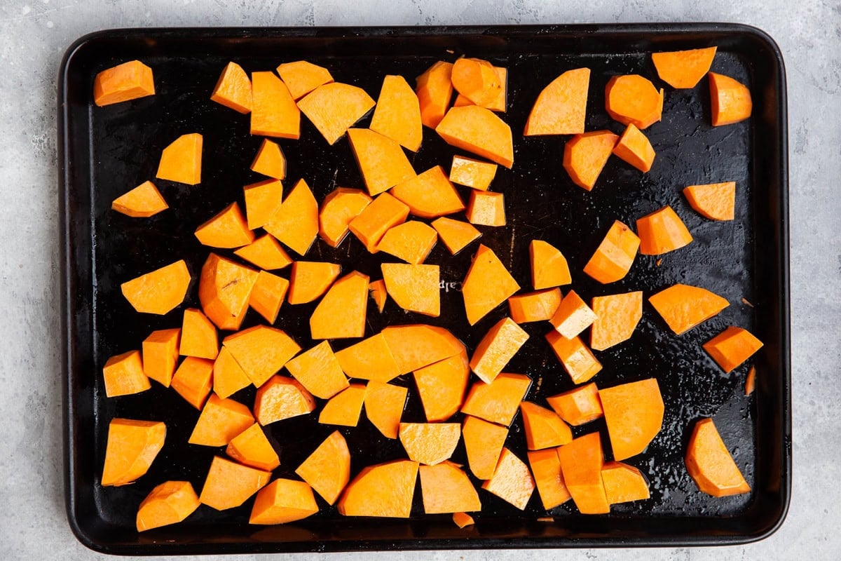 Baking sheet of chopped sweet potatoes in a layer, ready to bake.