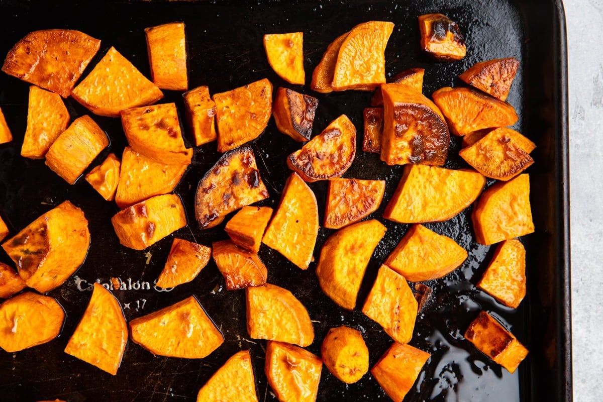 Baking sheet with roasted sweet potatoes on top, fresh out of the oven and golden brown.