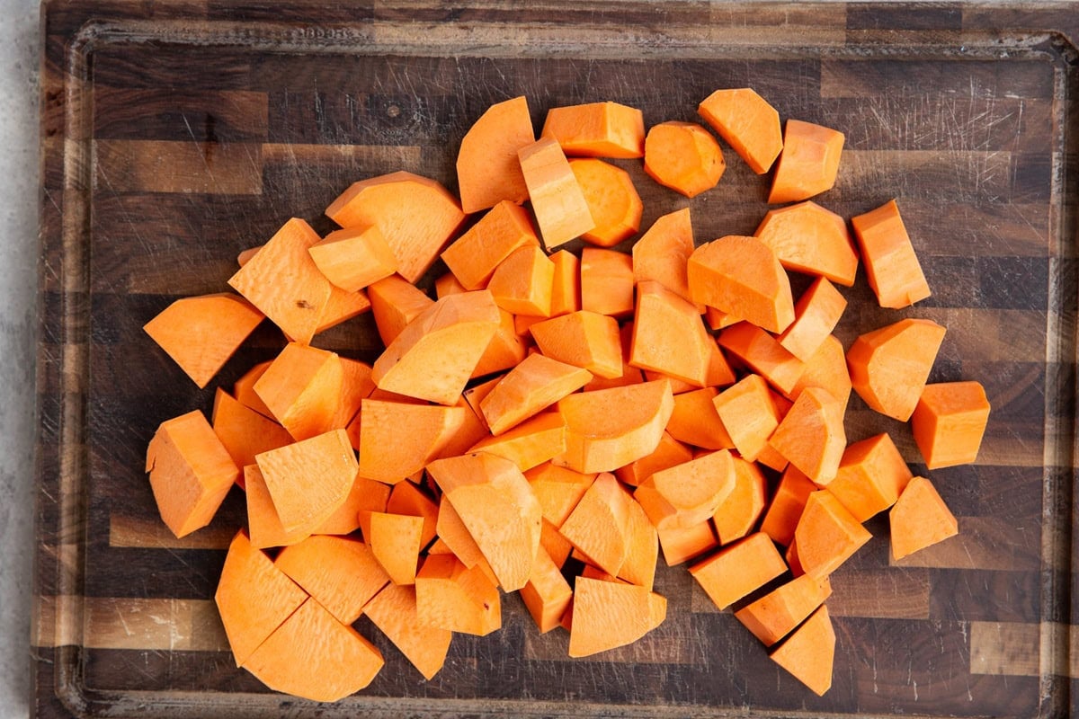 Chopped sweet potatoes on a wooden cutting board.