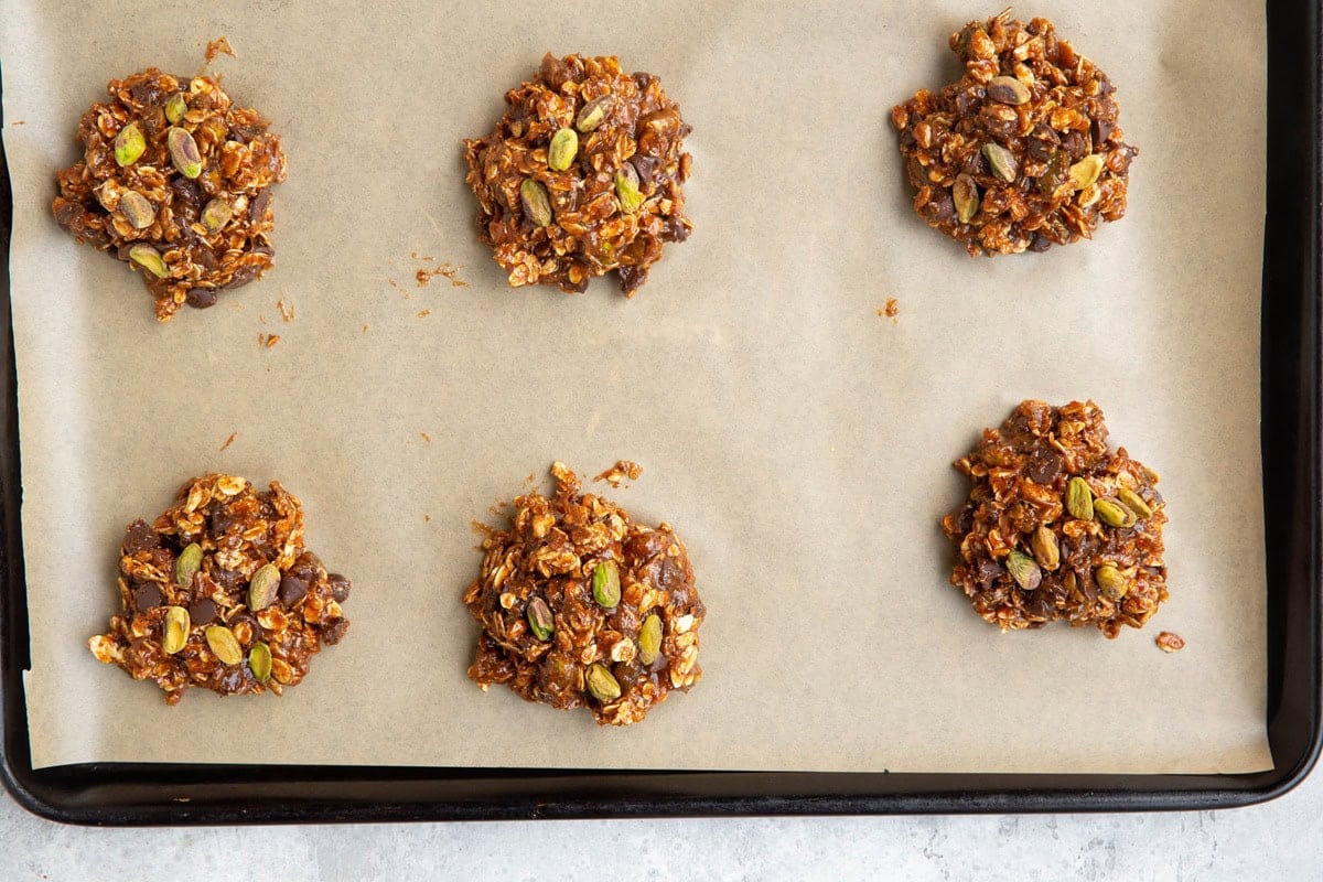 parchment-lined baking sheet with mounds of pistachio cookie dough on top.