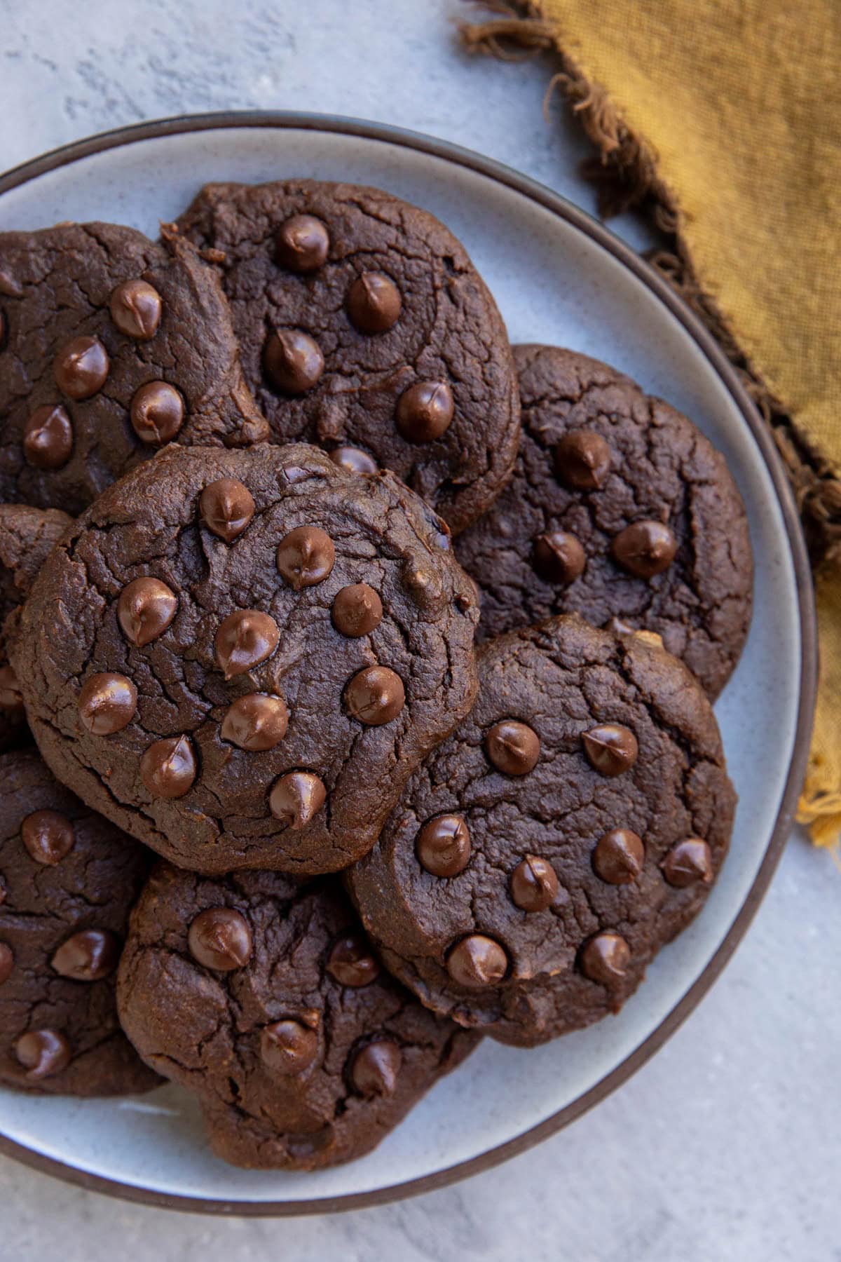 Plate full of chocolate pumpkin cookies, ready to eat with a golden napkin to the side.