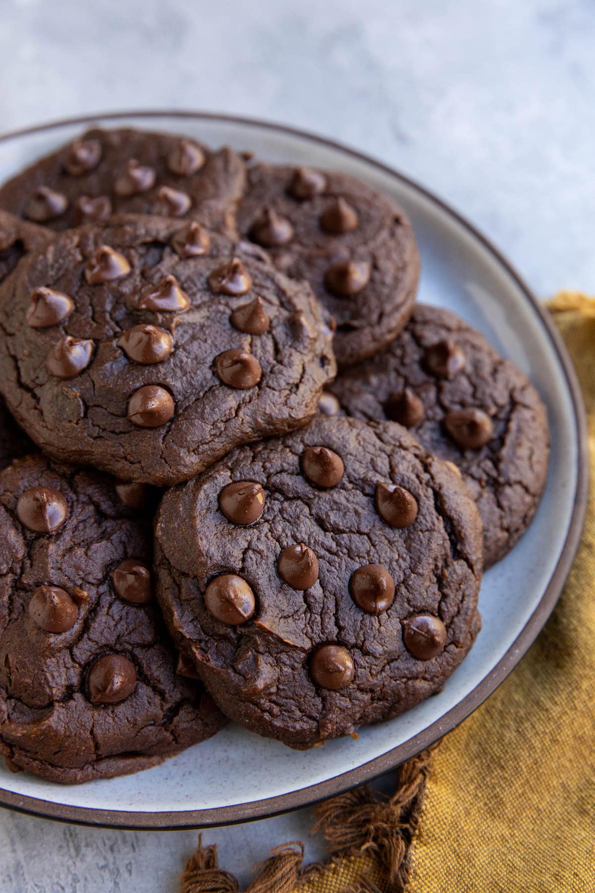 Chocolate pumpkin cookies on a plate with a golden napkin to the side.
