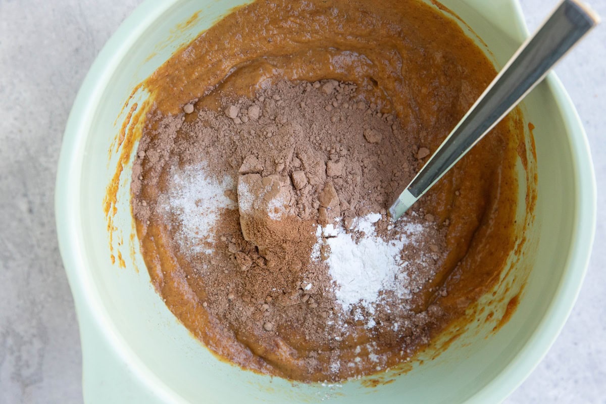 Wet ingredients in the bottom of a mixing bowl with dry ingredients on top, ready to be mixed in.
