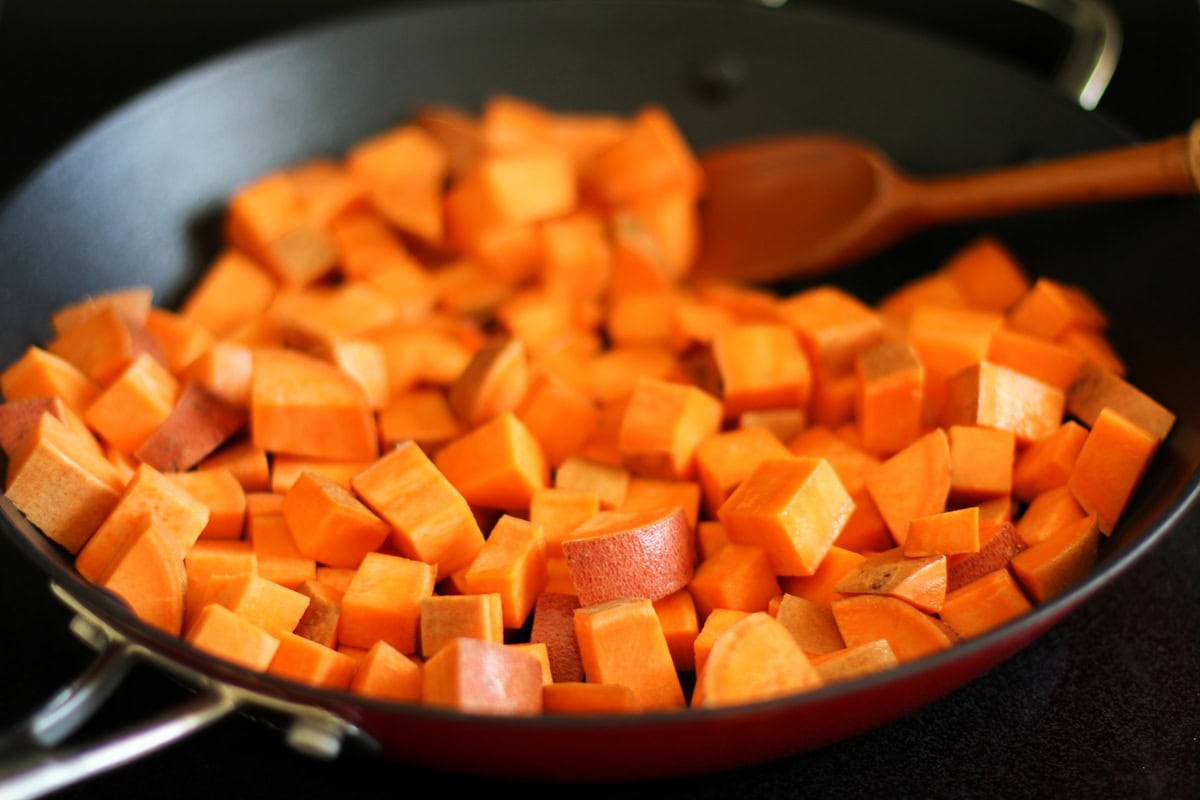 Chunks of sweet potato cooking in a skillet to make home fries.