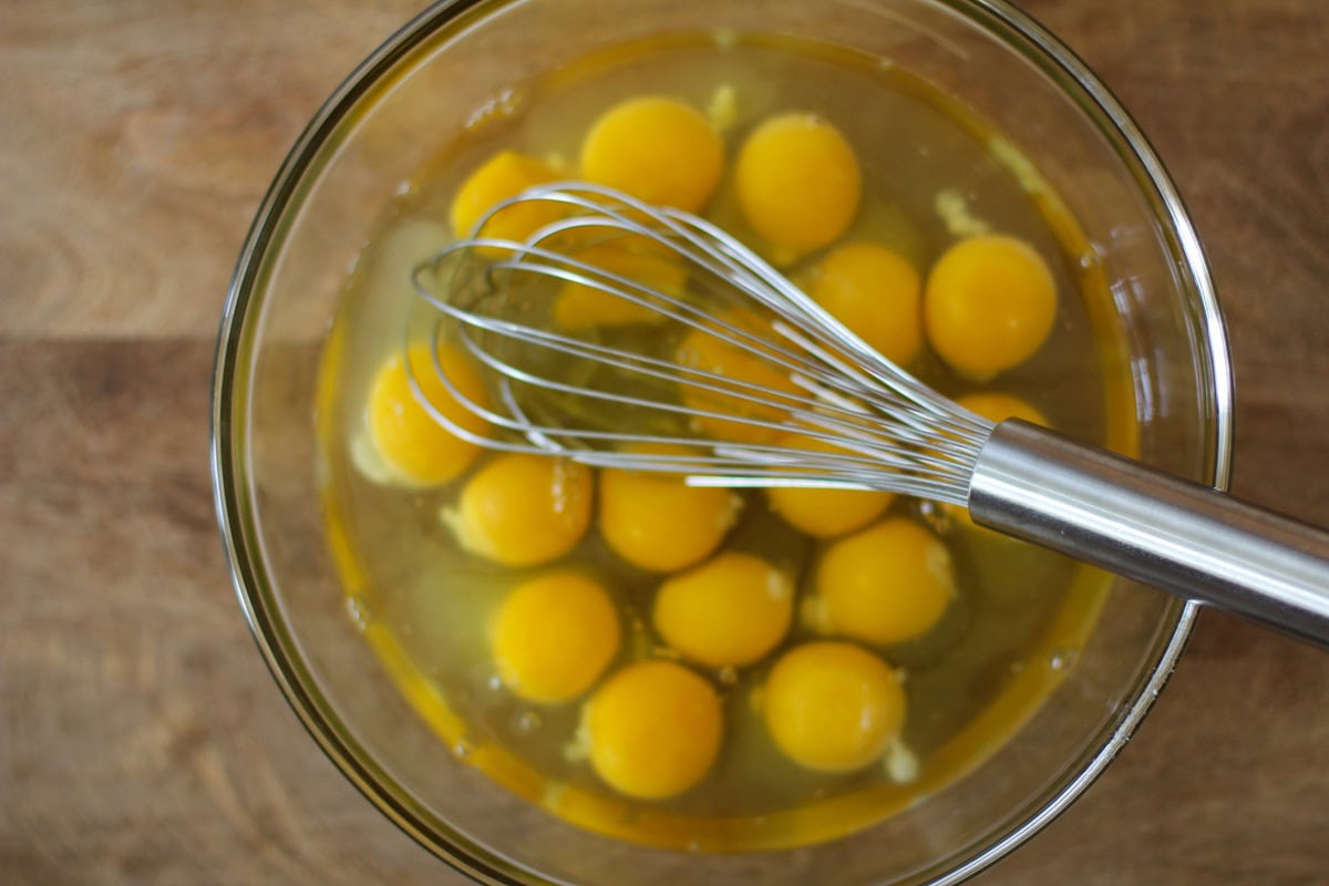 Eggs in a clear bowl with a whisk to be beaten.