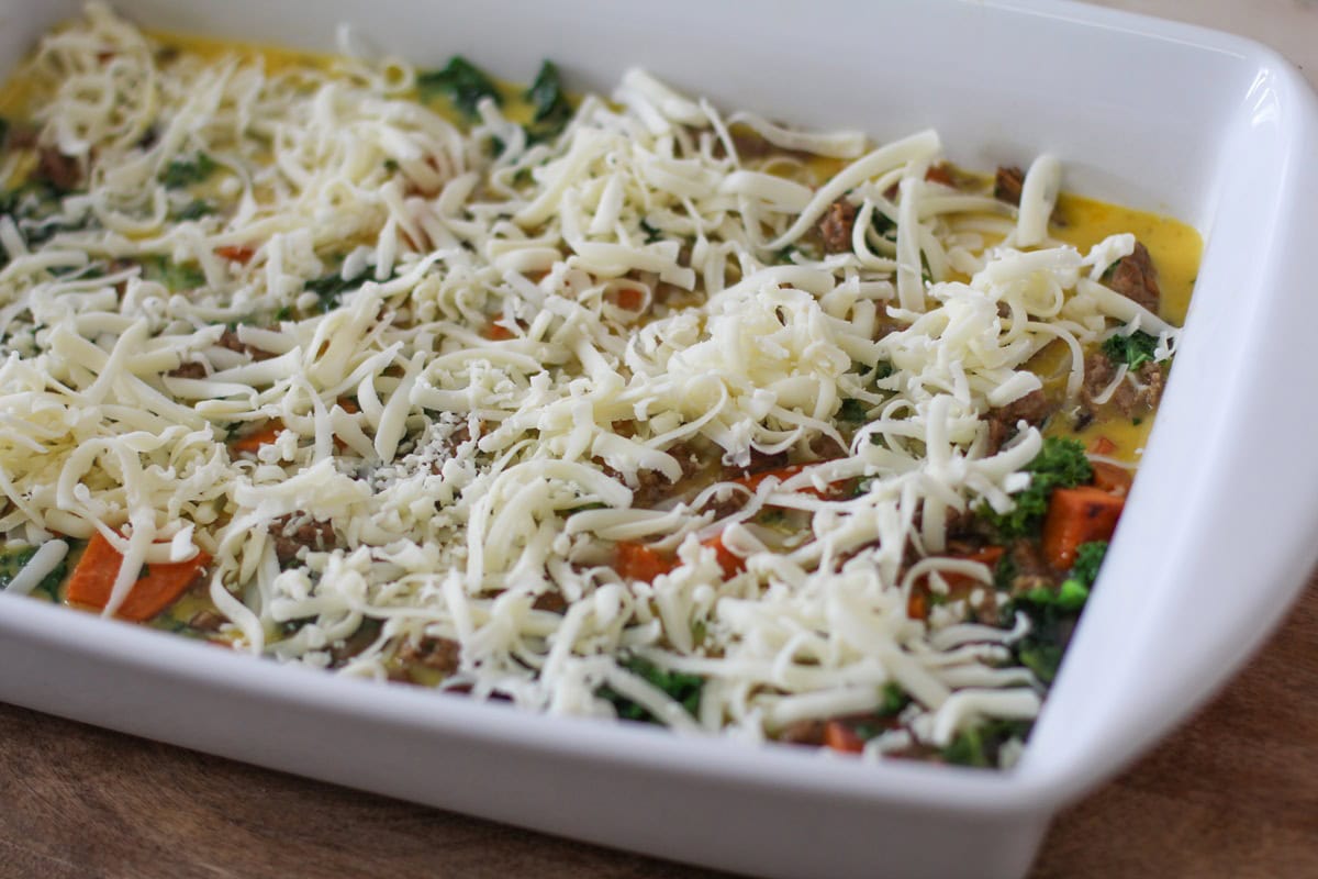 Grated cheese on top of breakfast casserole ingredients, ready to go into the oven.