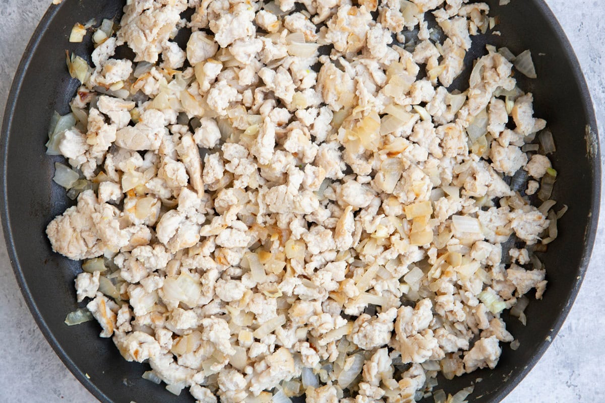 Onions and ground turkey cooking in a skillet.