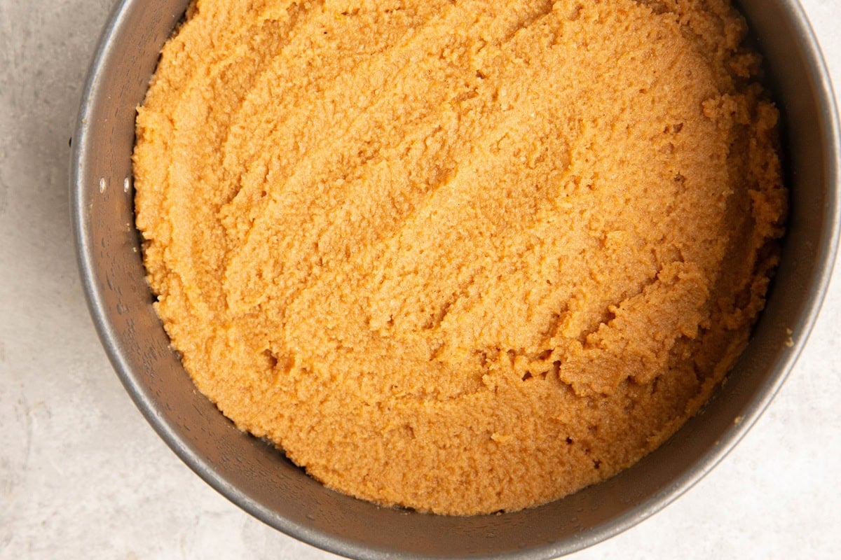 Cake pan with pumpkin cake batter spread evenly inside.