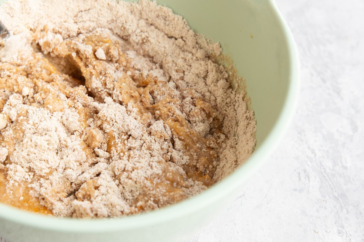 Mixing bowl with wet ingredients and dry ingredients being mixed together to make donut bread.