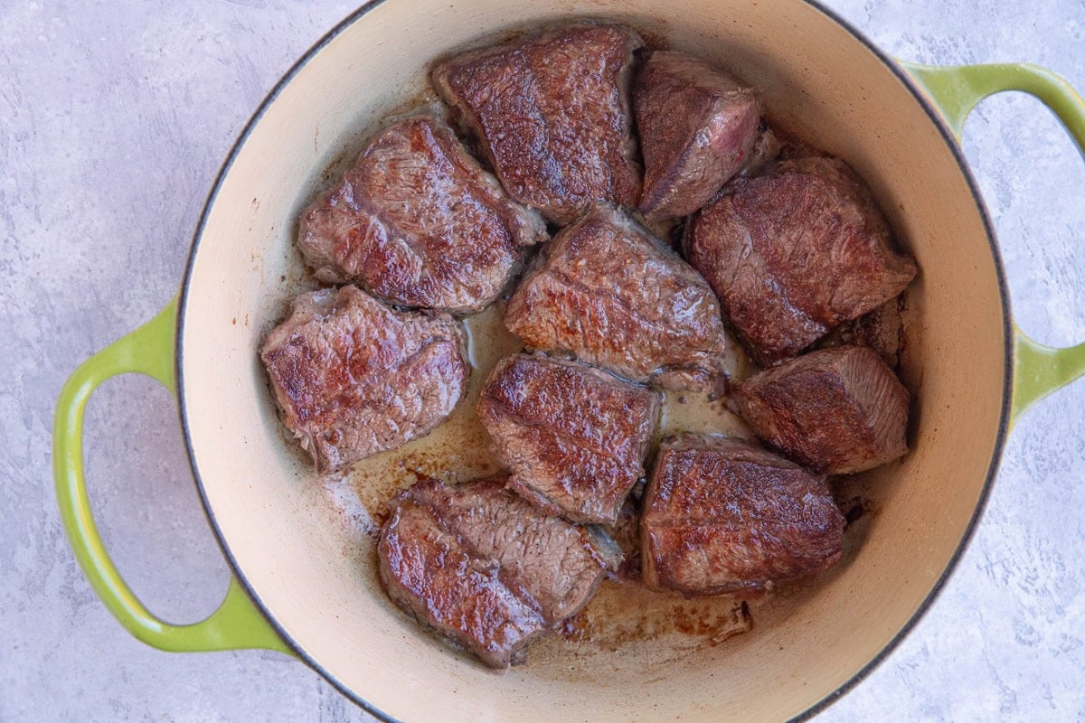 Dutch oven with chunks of browned beef to make birria soup.