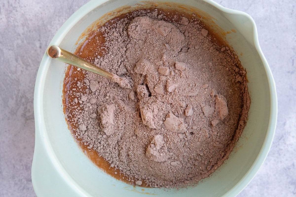 Mixing bowl with wet ingredients on the bottom and dry ingredients on top to make chocolate sweet potato bread.