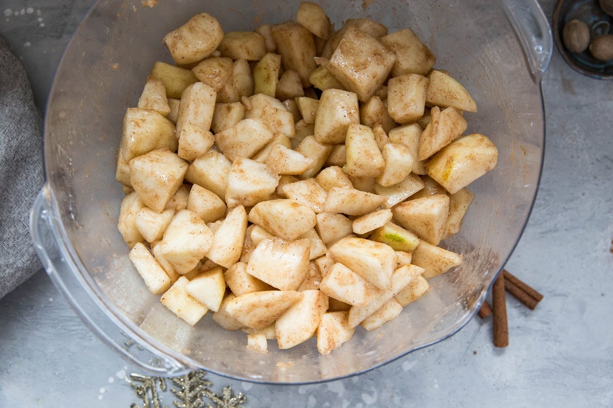 Pears tossed in warm spices in a mixing bowl.
