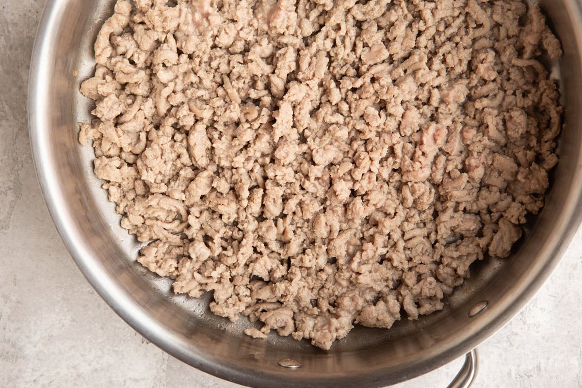 Ground turkey cooking in a stainless steel skillet