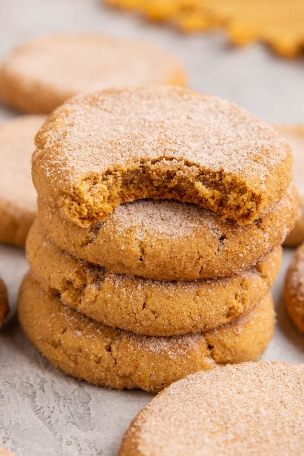 Stack of pumpkin snickerdoodles with more snickerdoodles all around.