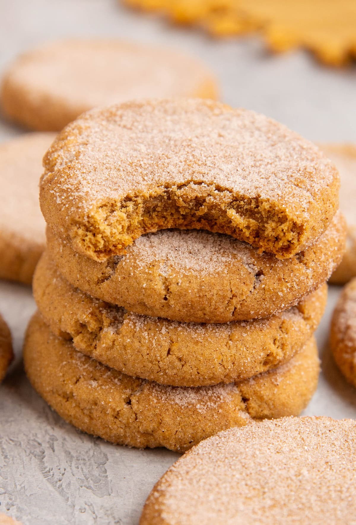 Stack of pumpkin snickerdoodles with more snickerdoodles all around.