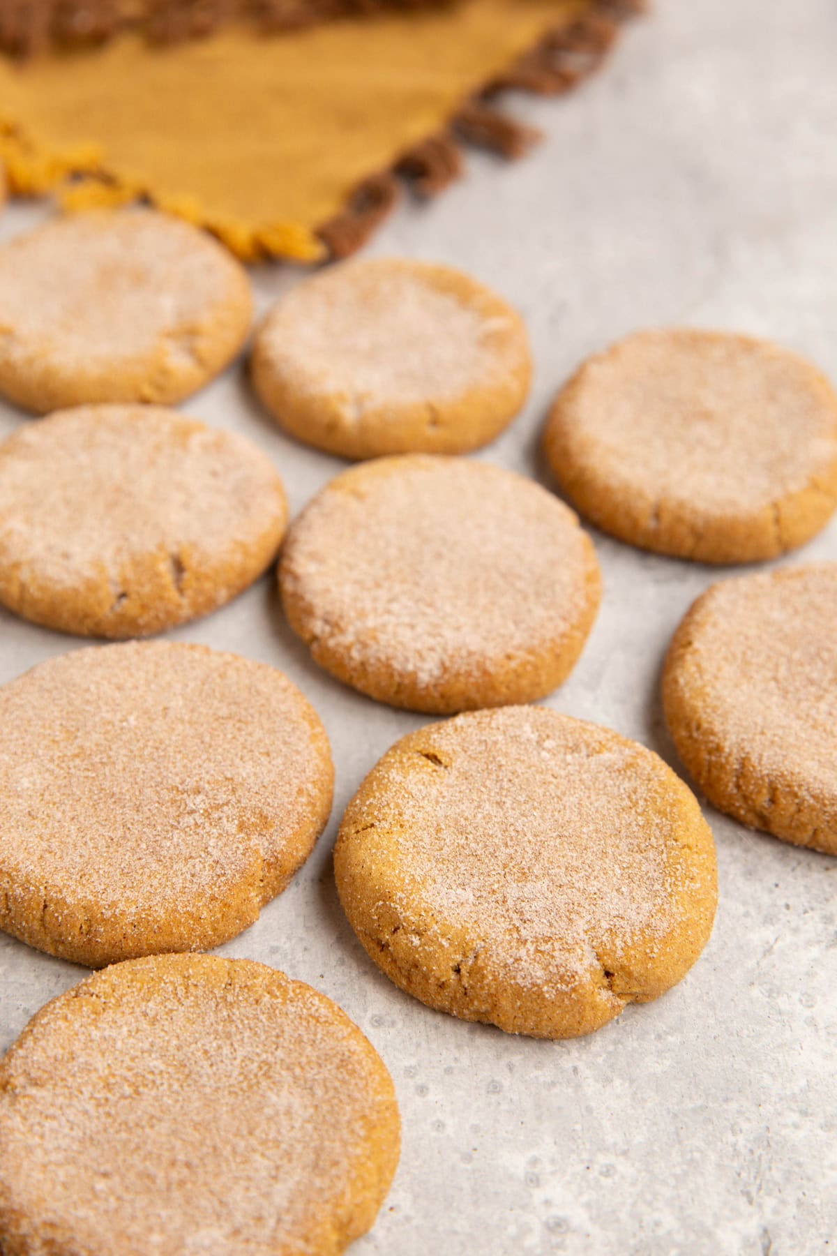 Pumpkin snickerdoodles on a backdrop with a golden napkin in the background.