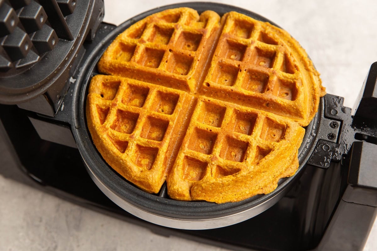Waffle iron with pumpkin waffle cooking. Golden brown and ready to serve