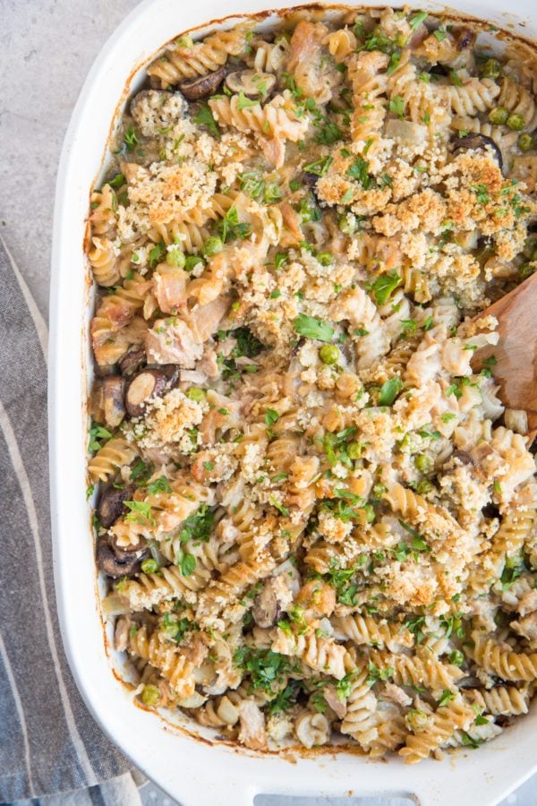 Salmon Noodle Casserole in a large white casserole dish with a wooden spoon to the side.