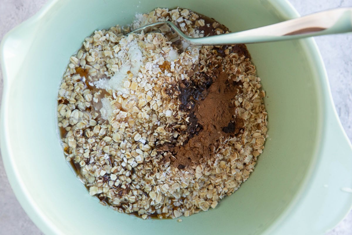 Mixing bowl full of flour, oats, pure maple syrup, cinnamon, and coconut oil to make a topping for the casserole.