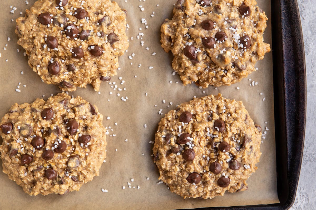 Baking sheet with tahini cookies on top, sprinkled with coarse sea salt.